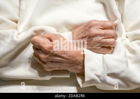 Les mains d'une femme âgée s'accrochée aux poings sur la poitrine. Banque D'Images