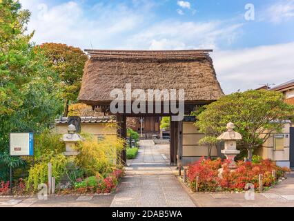 tokyo, japon - novembre 05 2020 : lanternes en pierre devant le toit de chaume brandi de la porte principale Tamonji-Sanmon dans le temple bouddhiste Tamonji de Banque D'Images
