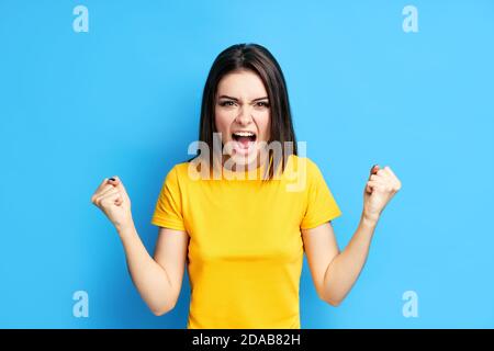 Hurler une jeune femme en colère sur fond bleu. Émotions négatives, haine, rage ou stress concept Banque D'Images