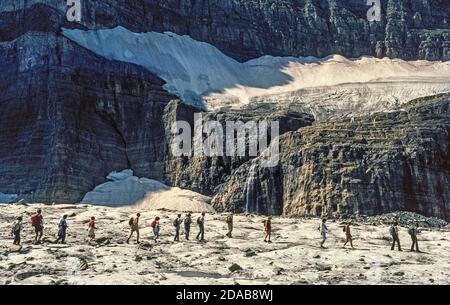 Une ligne de randonneurs lors d'une visite guidée par un garde-forestier traverse un reste glacial du glacier Grinnell, une attraction de longue date dans le parc national de Glacier, une vaste réserve sauvage dans le nord-ouest du Montana, aux États-Unis. Le glacier a été nommé pour George Bird Grinnell, un ancien restaurationniste qui a découvert le champ de glace en 1885 et a aidé la région vierge à être établie comme le 10e parc national de l'Amérique en 1910. Malheureusement, les nombreux glaciers pour lesquels le parc est nommé ont souffert des changements climatiques au fil des ans. D'environ 146 glaciers au milieu du XIXe siècle, il ne reste plus que 26 glaciers nommés. Banque D'Images