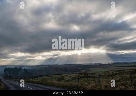 Ciel sombre et rayons de soleil traversant au-dessus des landes au sud de Rothbury, à Northumberland, Angleterre, Royaume-Uni Banque D'Images