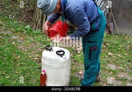 Le fermier verse le jus de pomme dans un baril de la manière traditionnelle de making must dans le village Banque D'Images