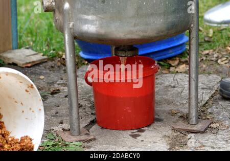 Le fermier verse le jus de pomme dans un baril de la manière traditionnelle de making must dans le village Banque D'Images