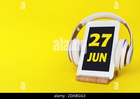 27 juin. Jour 27 du mois, date du calendrier. Casque élégant et tablette moderne sur fond jaune. Espace pour le texte. Éducation, technologie, style de vie Banque D'Images