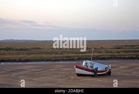 Un homme travaillant sur un bateau de pêche à basse eau dans le ruisseau Overy, sur la côte nord du Norfolk, à Burnham Overy Staitha, Norfolk, Angleterre, Royaume-Uni. Banque D'Images