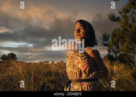 jeune femme avec confiance regarder le lever du soleil en plein air avec robe et ciel nuageux. concept de femme indépendante moderne faisant des choix et regardant un Banque D'Images