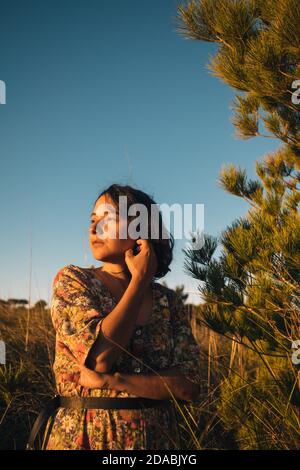 jeune femme avec confiance regarder le lever du soleil en plein air avec robe et ciel nuageux. concept de femme indépendante moderne faisant des choix et regardant un Banque D'Images