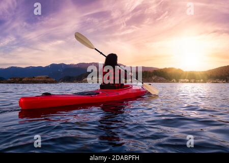 Aventure fille pagayant sur un kayak rouge vif Banque D'Images