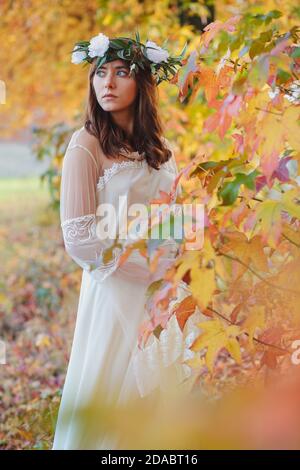 Magnifique jeune fille d'automne avec couronne. Des feuilles colorées comme arrière-plan Banque D'Images