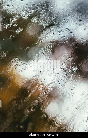 Reflet flou de la rue dans une fenêtre embuée, gouttes d'eau après la pluie coule dans le verre. Gouttes d'eau sur la fenêtre. Concept d'humeur pluvieuse. Banque D'Images