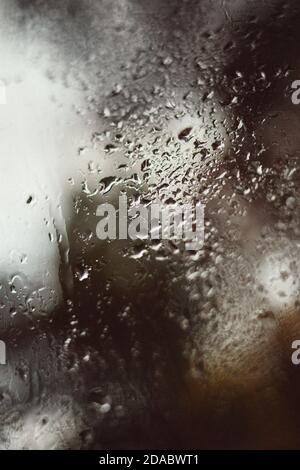 Reflet flou de la rue dans une fenêtre embuée, gouttes d'eau après la pluie coule dans le verre. Gouttes d'eau sur la fenêtre. Concept d'humeur pluvieuse. Banque D'Images