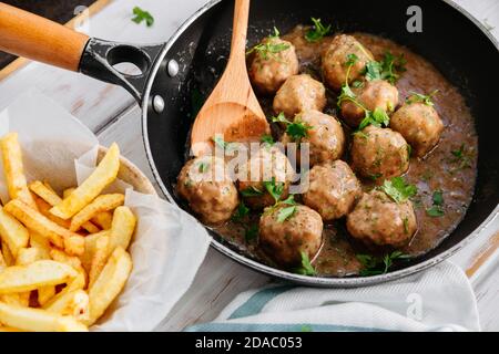 Boulettes de viande en sauce à l'oignon et persil dans une poêle à frire et frites Banque D'Images
