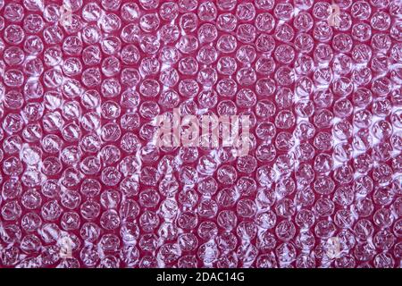 film à bulles en plastique sur fond rouge, vue du dessus Banque D'Images