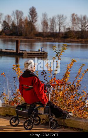 Un homme plus âgé se reposant sur son marcheur à roulettes et bénéficiant d'un soleil d'automne Dans Steveston Colombie-Britannique Canada Banque D'Images