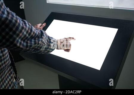 Image de gros plan de Mockup: Homme main touchant blanc vide écran tactile interactif kiosque dans la pièce sombre du musée de la technologie. Maquette, modèle, scifi Banque D'Images