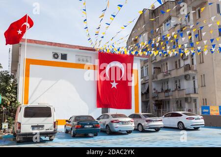 Un grand drapeau turc est suspendu à la façade de la maison au-dessus des parkings de la rue. Rues de la ville décorées. Alania, Turquie Banque D'Images