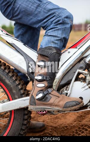 Vue rapprochée de la botte de motocross se tenant sur la cheville de la moto d'essai. Chaussures et vêtements de sécurité pour la conduite Banque D'Images