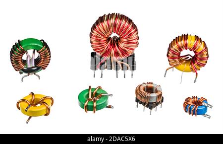 Ensemble de bobines d'induction électroniques ou de transformateurs isolés sur fond blanc. Diverses inductances toroïdales avec enroulement de fil de cuivre et noyau en ferrite. Banque D'Images