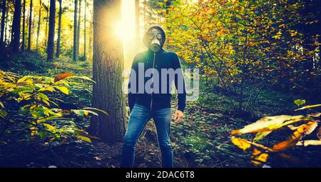 Homme avec masque à gaz dans la forêt au coucher du soleil Banque D'Images