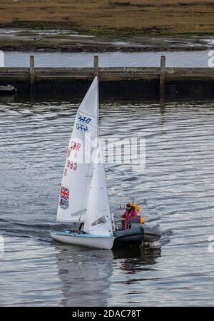 un petit canot de course étant remorqué dans la marina de lymington par une côte après avoir été séduit avec maintenant ind sur une journée calme. Banque D'Images