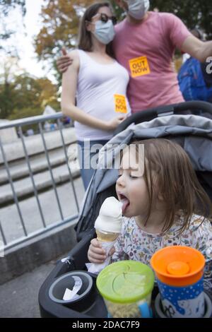 L'enfant aime le cône de glace tandis que ses parents célèbrent la victoire présidentielle de Joe Biden lors d'une manifestation de célébration au Columbus Circle à New York le 7 novembre 2020 Banque D'Images