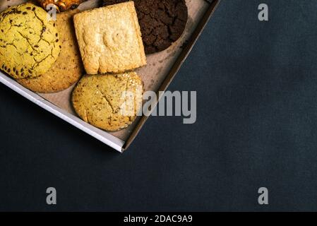 Divers types de pâtisseries sucrées sont dans une boîte en carton. Gros plan de gâteaux faits maison cuits avec espace de copie. Boîte cadeau avec pâtisseries. Vue de dessus, plan d'appartement Banque D'Images