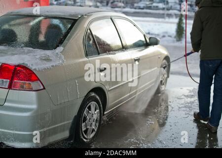 L'homme lave son automobile au poste de lavage manuel en hiver Banque D'Images