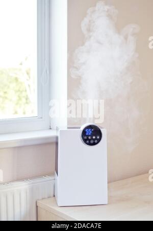 Humidificateur d'air avec vapeur sur la table près du fenêtre et radiateur  de chauffage au salon ou à la chambre Photo Stock - Alamy