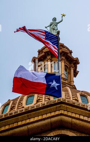 Drapeau américain et texan battant devant le dôme du bâtiment de la capitale de la maison d'État à Austin. Banque D'Images