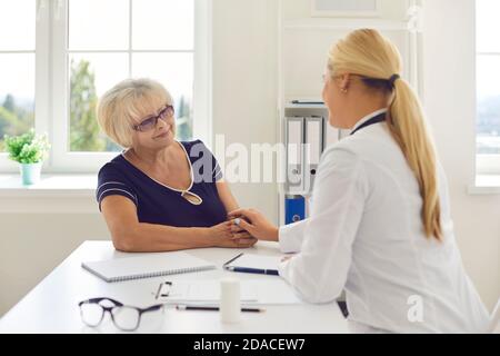 Une femme médecin tient la main de sa patiente âgée dans une chambre d'hôpital comme signe de soutien. Banque D'Images