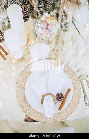 Table en verre festive du nouvel an. Carte de vœux. Dans les branches de l'arbre de Noël sont des verres à champagne, des couverts, une assiette avec dorure Banque D'Images