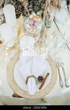 Table en verre festive du nouvel an. Carte de vœux. Dans les branches de l'arbre de Noël sont des verres à champagne, des couverts, une assiette avec dorure Banque D'Images