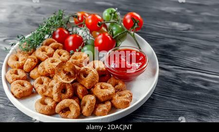 Tarallini fait main avec des tomates et des herbes est appelé taralli ou TALRALLINI. Produits dans les boulangeries italiennes du sud de l'Italie. Petits anneaux à grignoter sur un Banque D'Images