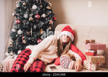 Femme endormi et fatiguée de l'emballage cadeau avec le chiot Chien sur un canapé dans le salon avec Noël arbre à la maison Banque D'Images