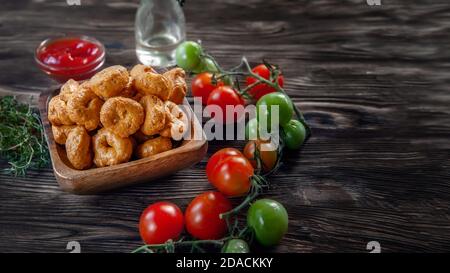 Tarallini fait main avec des tomates et des herbes est appelé taralli ou TALRALLINI. Produits dans les boulangeries italiennes du sud de l'Italie. Petits anneaux à grignoter sur un Banque D'Images
