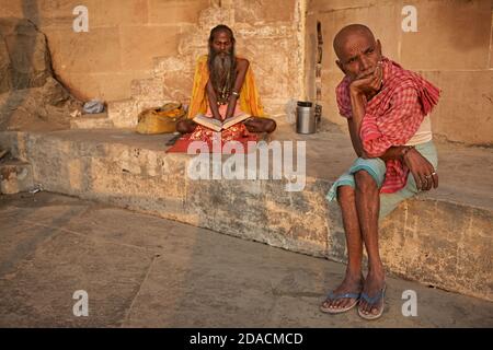 Varanasi, Inde, octobre 2011. Un Sadhu lit un livre Saint dans un ghat sur le Gange. Banque D'Images