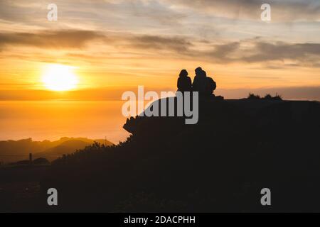 Silhouettes d'amis voyageurs en haut d'une colline regardant un beau coucher de soleil et parler, Californie, États-Unis Banque D'Images