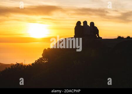 Silhouettes d'amis voyageurs en haut d'une colline regardant un beau coucher de soleil et parler, Californie, États-Unis Banque D'Images