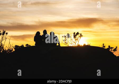 Silhouettes d'amis voyageurs en haut d'une colline regardant un beau coucher de soleil et parler, Californie, États-Unis Banque D'Images