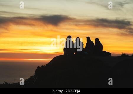 Silhouettes d'amis voyageurs en haut d'une colline regardant un beau coucher de soleil et parler, Californie, États-Unis Banque D'Images