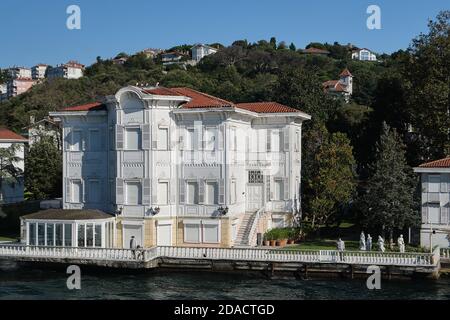 Vue depuis un bateau de croisière sur le Bosphore d'une maison de style européen vintage au bord de la rivière avec des lattes en bois et des volets et des statues sur la pelouse, Istanbul, Banque D'Images