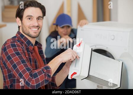 réparateur tenant le condensateur du sèche-linge Banque D'Images