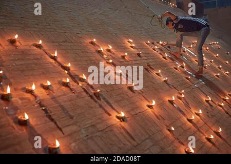 Varanasi, Inde, novembre 2015. Un jeune homme éclaire des bougies dans un ghat sur le fleuve Ganges la nuit. Banque D'Images