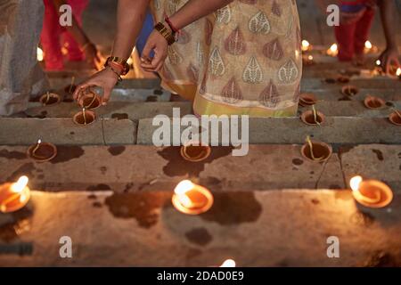 Varanasi, Inde, novembre 2015. Gros plan d'une femme allumant des bougies dans un ghat sur le fleuve Ganges la nuit. Banque D'Images