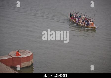 Varanasi, Inde, novembre 2011. Un saddhu regardant un bateau naviguant sur le Gange. Banque D'Images