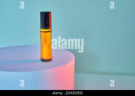 Flacon compte-gouttes pour flacons à parfum sans étiquette sur fond blanc avec lumières colorées. Banque D'Images