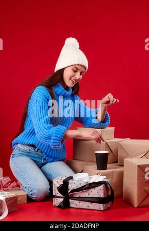 une fille dans un chapeau verse du sucre dans un fond rouge de café. Banque D'Images