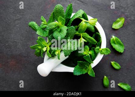 Feuilles de menthe fraîche dans le mortier sur table en pierre. Vue d'en haut Banque D'Images