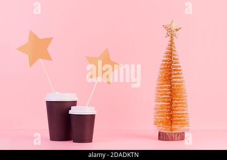 Deux tasses en papier noir avec arbre de noël doré et autocollant vierge sur fond rose, modèle de publicité, design, café, restaurant Banque D'Images