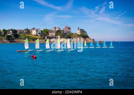 Quelques voiliers alignés et ancrés au milieu de la baie de Dinard avec de belles demeures construites sur sa côte. Bretagne, France Banque D'Images